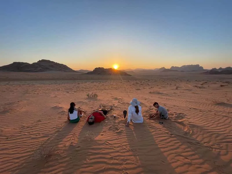 Red sand dunes and sandstone cliffs in Wadi Rum desert at golden hour during a sunset jeep tour, Jordan