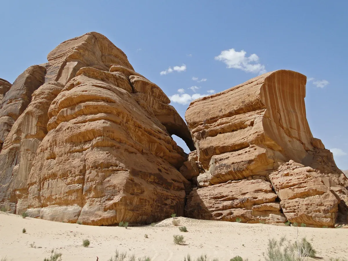 Sandstone walls and a natural rock arch under a clear sky in Wadi Rum, Jordan, in the best daylight months for a visit
