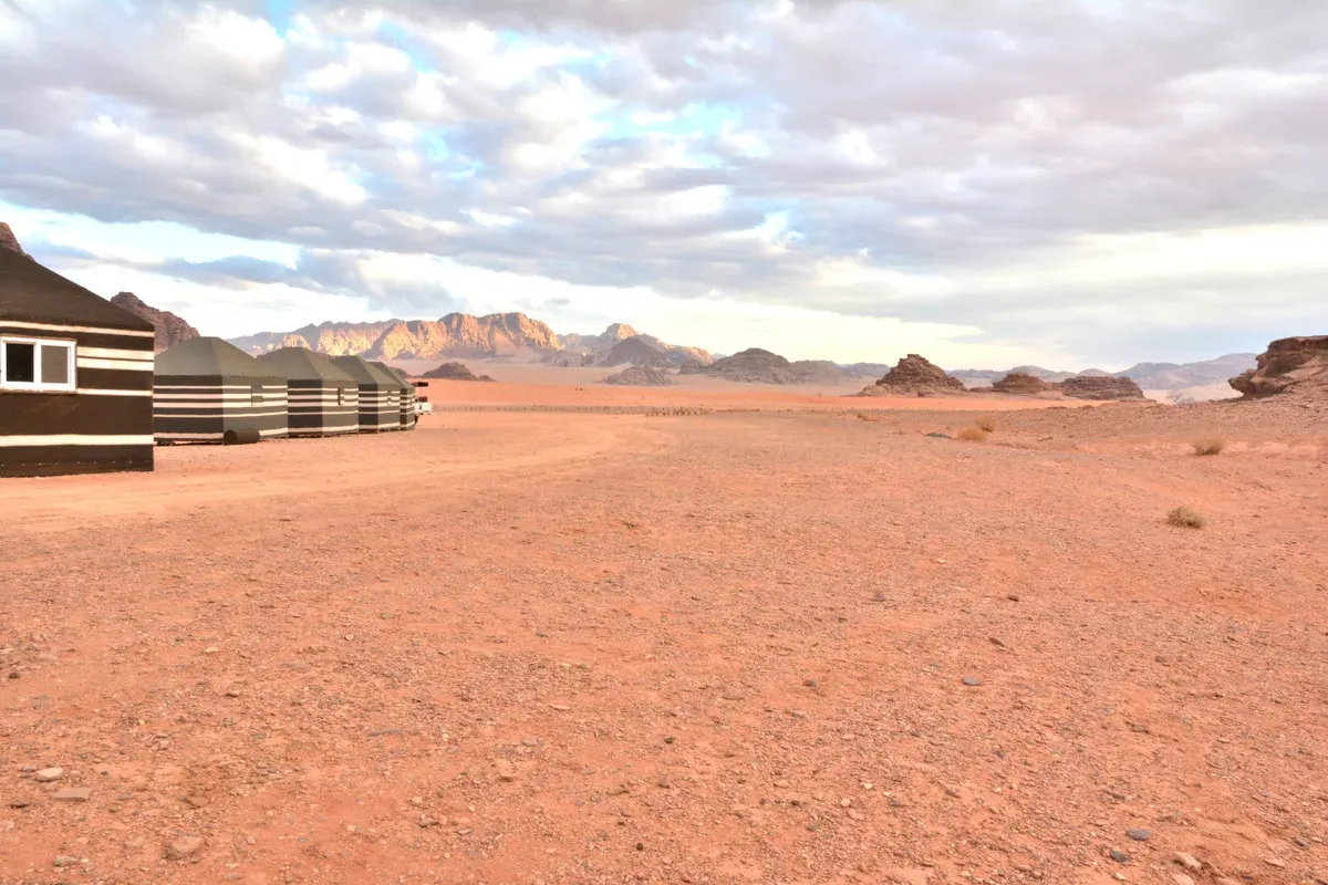 A row of striped Bedouin camp tents on red gravel in Wadi Rum, Jordan, a desert tour price tier of its own